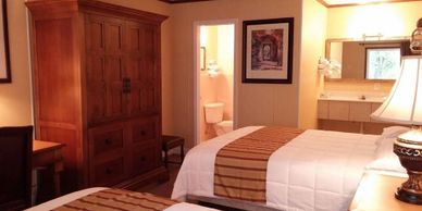 Cozy hotel room with two beds and wooden furniture.