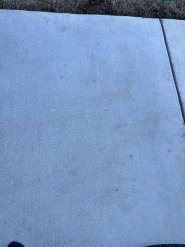A concrete sidewalk with a tire and part of a shoe visible.