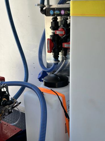Close-up of a water filtration and mixing system with blue hoses and red valves.