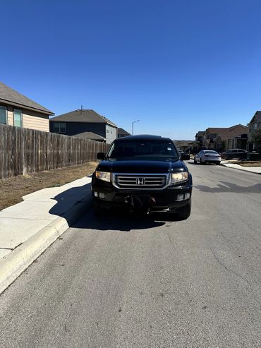 Black Honda SUV parked on a residential street under clear blue sky.