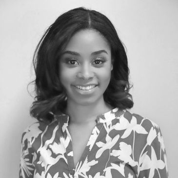 Smiling woman in floral patterned blouse against plain background.