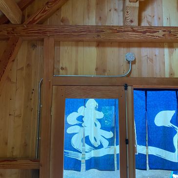 Wooden interior with a door covered by blue fabric curtains with white designs.