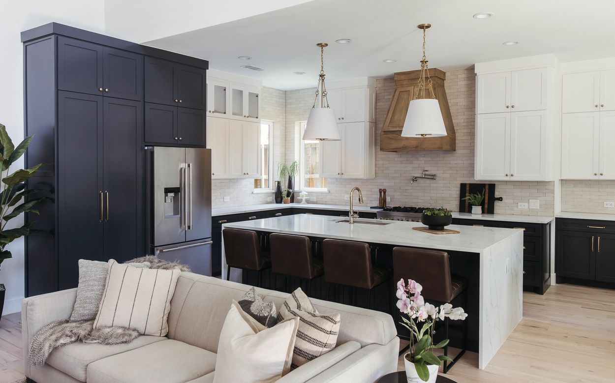 Grapevine kitchen with navy cabinetry, white perimeter cabinets, large island, wood range hood, and statement pendant lighting.