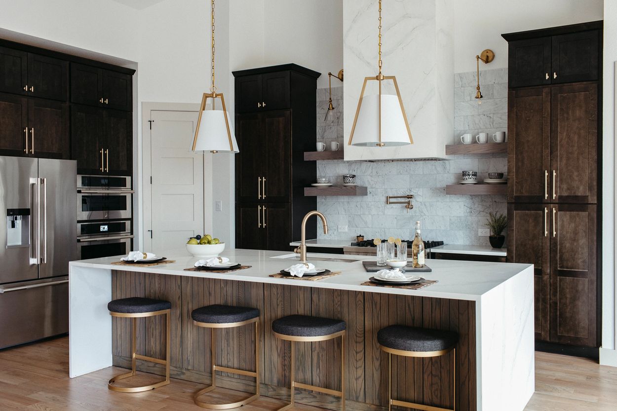 Grapevine kitchen with dark cabinetry, white waterfall island, marble backsplash, open shelving, and modern pendant lighting.