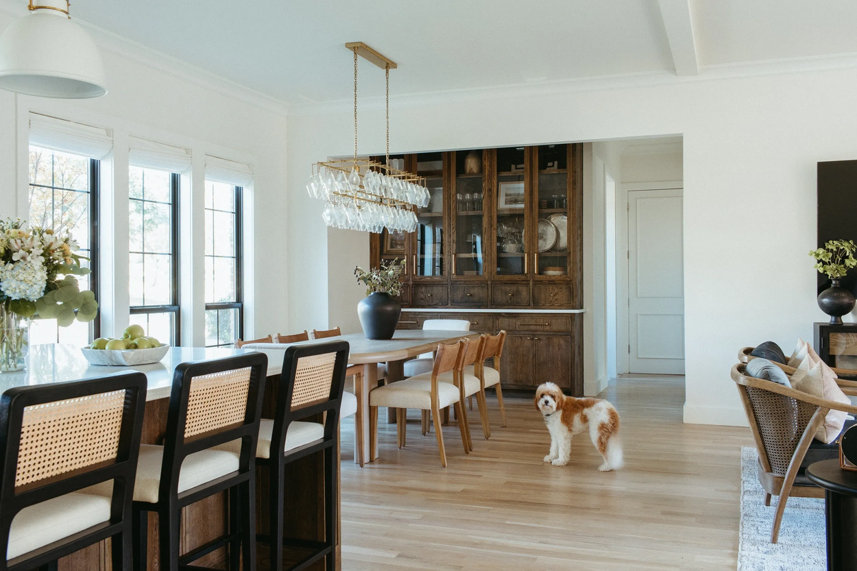 Bright Southlake kitchen and dining room with white cabinetry, natural wood island, and black-framed windows.