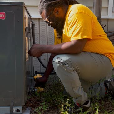 Technician repairing an outdoor HVAC unit on a sunny day.