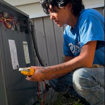 A young man working on an electrical panel outdoors.