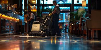 Worker cleaning a shiny restaurant floor with a floor scrubber.