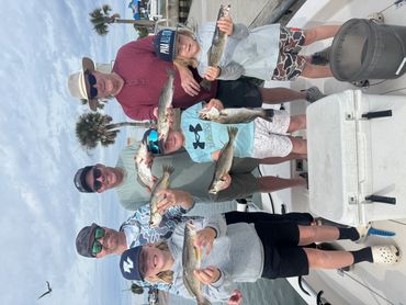 Family proudly showing their caught fish on a boat.