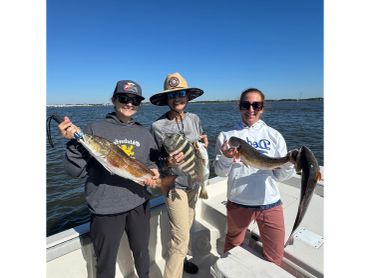 Three people proudly holding their catch on a boat.