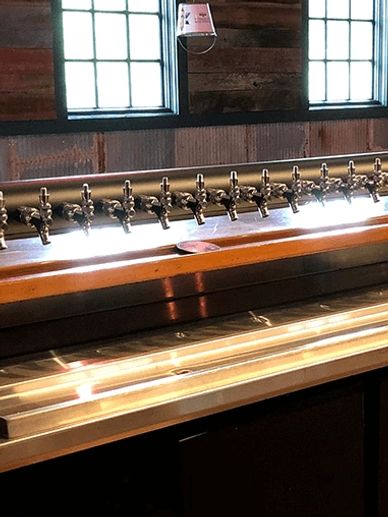 Long beer tap tower with multiple taps on a bar counter.
