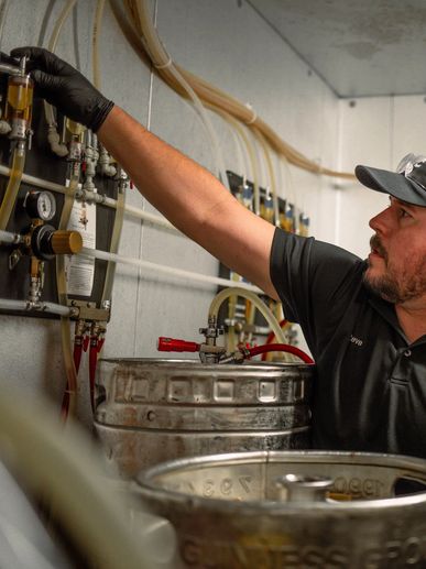 Man adjusting beer tap system connected to kegs.