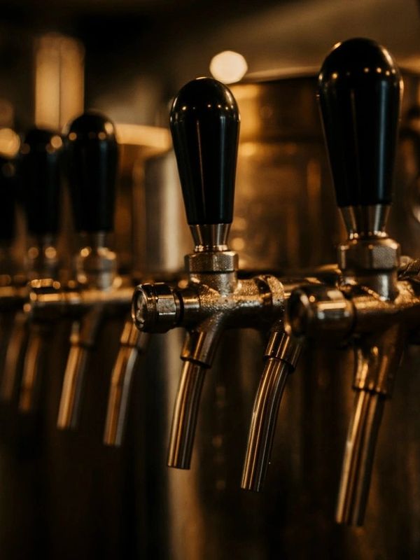 Close-up of beer taps in a dimly lit bar.