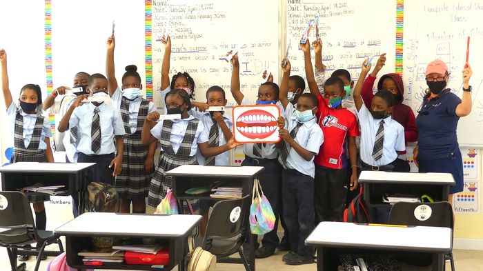 Heidi and Bahama classroom holding up toothbrushes and tooth board