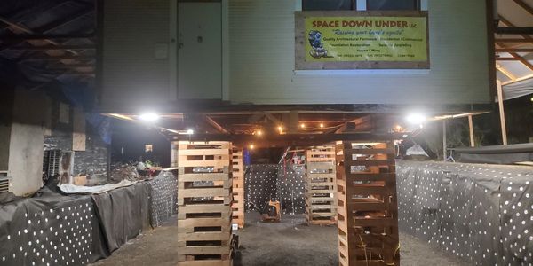 Indoor setup with wooden pallets and a sign for Space Down Under LLC.