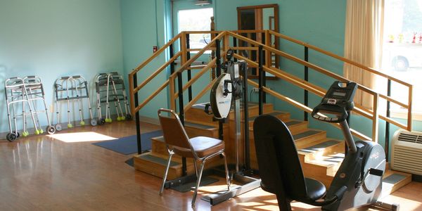 Physical Therapy room with stairs, recumbent bike, and hand therapy machine.