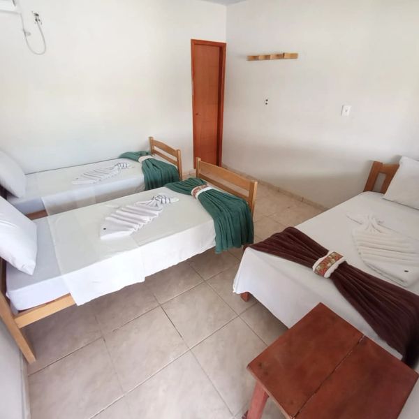 Quarto simples com três camas e decoração minimalista.