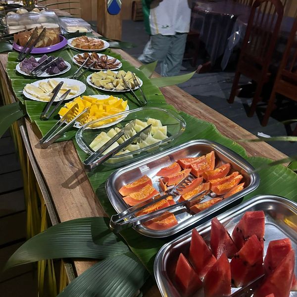 Mesa com variedade de frutas cortadas em bandejas.