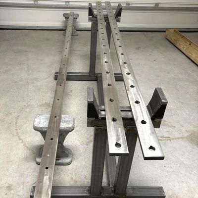 Metal bars with holes on a workshop bench.