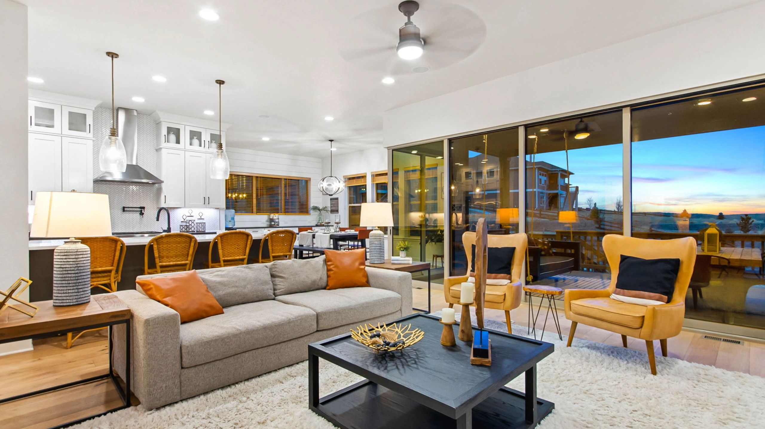 Modern open-concept living room and kitchen with large windows and cozy seating.