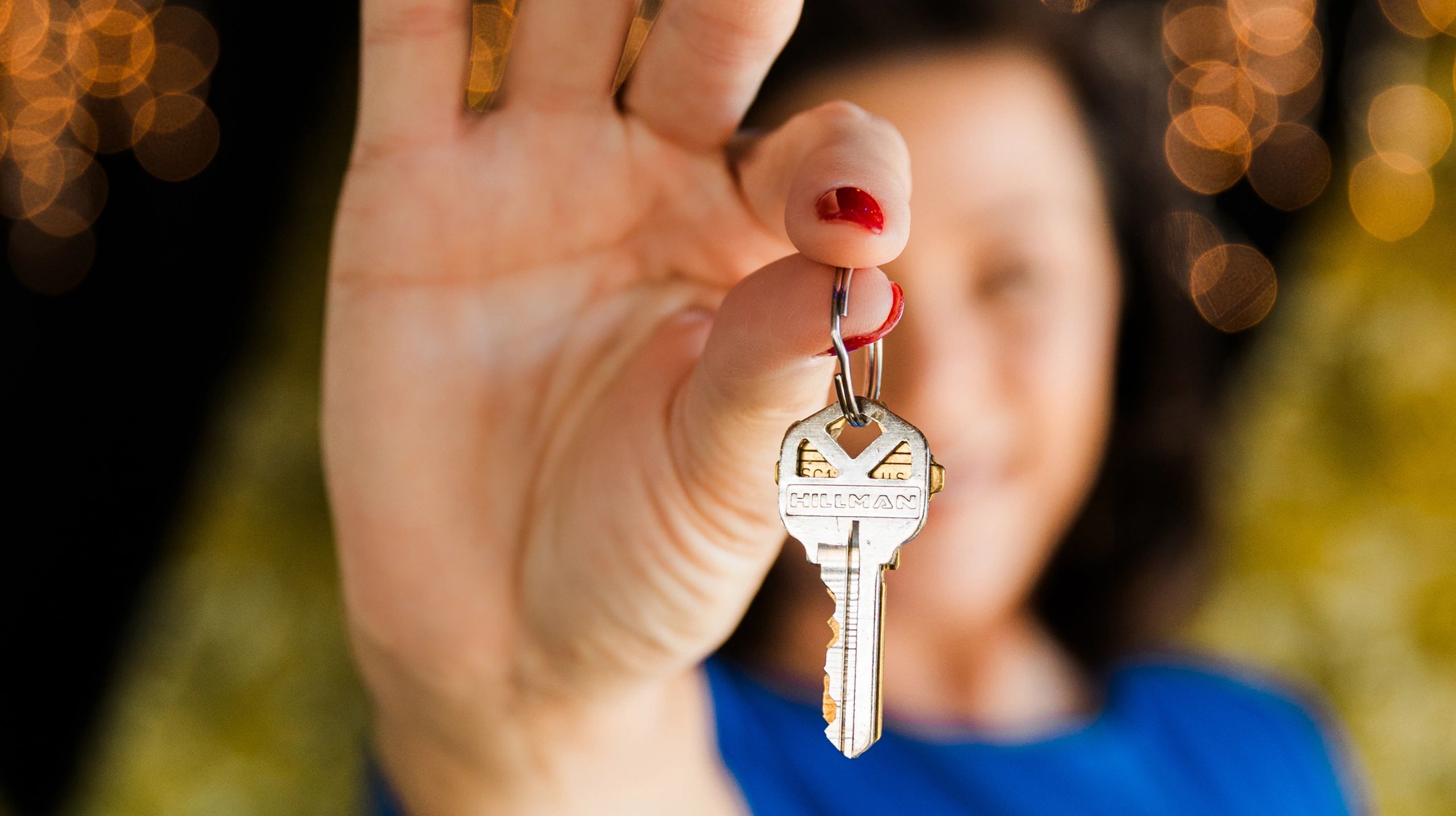 Person holding a key with red nail polish in focus.