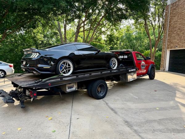 Black sports car on a red flatbed tow truck.