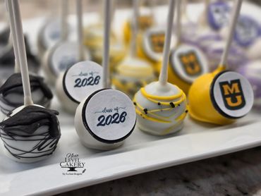 Graduation-themed cake pops decorated with class of 2026 and university logos.