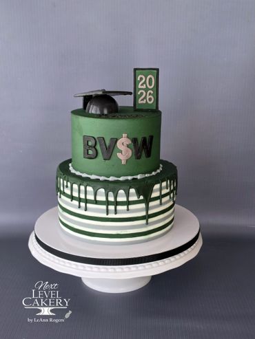 A green and white graduation cake with a cap and year 2026 topper.