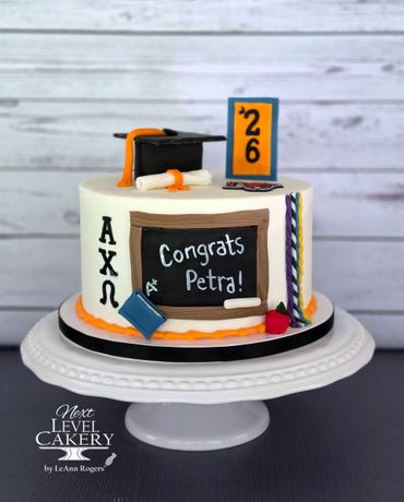 Graduation-themed cake with a cap, diploma, and chalkboard message.