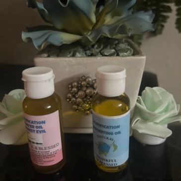 Two small bottles of anointing oil with decorative flowers and a succulent plant.