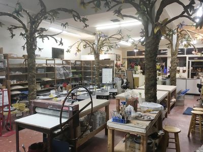 A pottery studio with tree-like sculptures and worktables filled with tools and materials.
