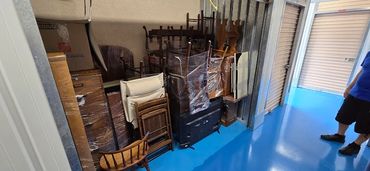 A storage unit filled with wrapped furniture and a person standing inside.