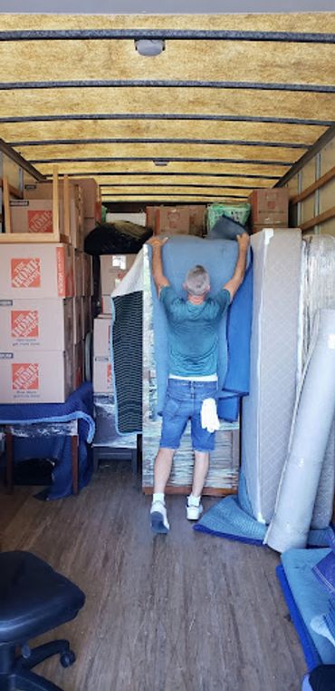 Man arranging furniture and boxes inside a moving truck.