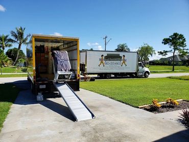 Two moving trucks in a residential driveway on a sunny day.