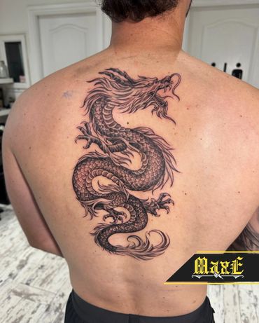 Intricate black dragon tattoo covering the upper back with detailed scales and fierce expression.