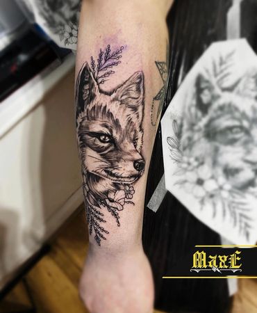 Detailed black and grey fox tattoo with floral accents on forearm.