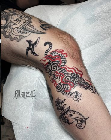 Intricate black and red tiger tattoo on a person's leg with additional tribal designs.