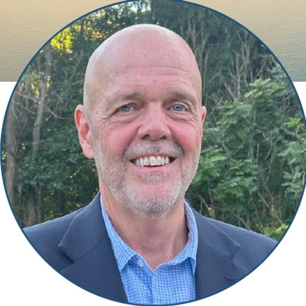 Smiling bald man in a suit outdoors.