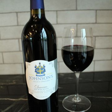 Bottle of Johnson's Legacy Vineyard red wine with a filled glass beside it.