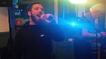 Man singing into a microphone with stage lights.