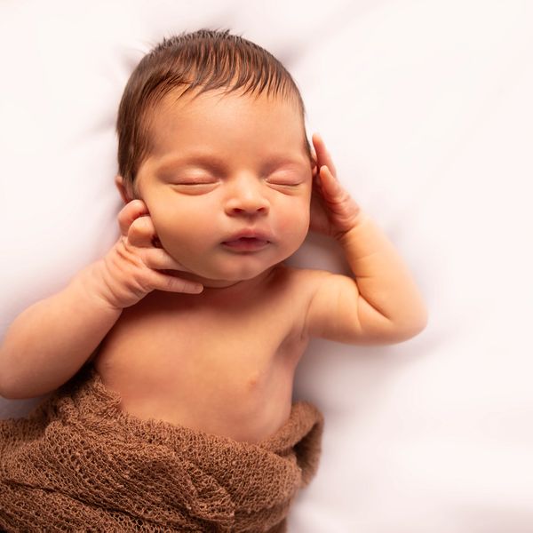 Sleeping newborn baby wrapped in a brown blanket.