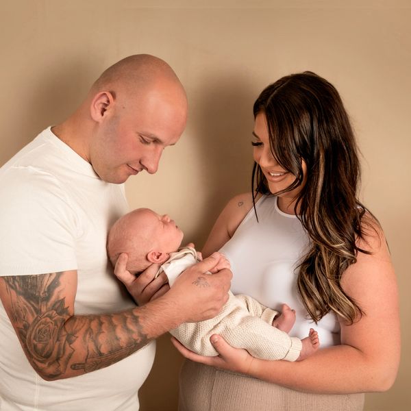 Parents lovingly hold their newborn baby together.