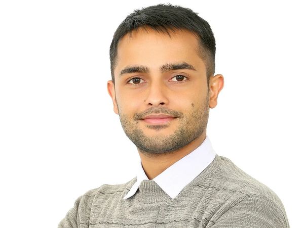 Portrait of a confident young man in a gray sweater against a white background.