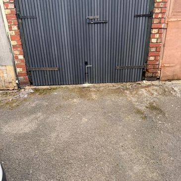 Closed gray garage door with brick framing and a concrete driveway.