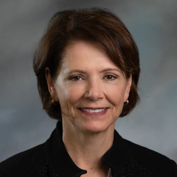 Professional portrait of a middle-aged woman with short brown hair.