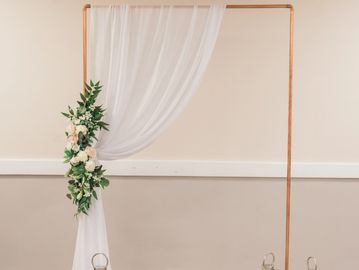 Dressed copper archway creating an elegant statement feature for wedding venue styling