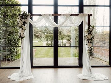Dressed wooden archway creating a romantic ceremony backdrop for wedding styling
