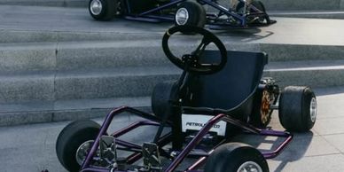 Two go-karts parked on pavement near stairs.