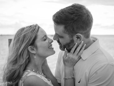 Couple sharing an intimate moment by the sea in black and white.