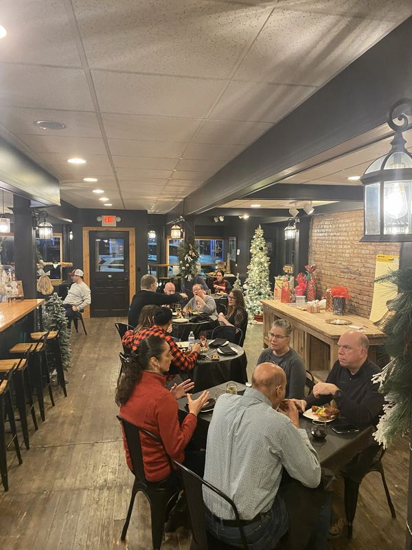 Cozy restaurant with diners enjoying meals amid Christmas decorations.
